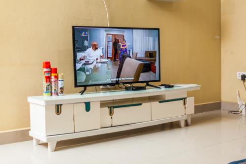 a living room with a television on a white entertainment center at Wangu Apartments in Livingstone