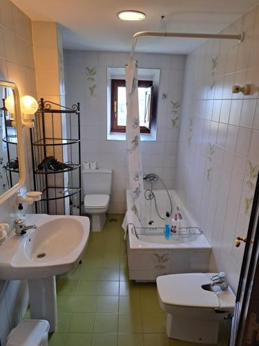 uma casa de banho com um lavatório, uma banheira e um WC. em Palacio Marqués Vega de Anzo - Villa de campo sXVII em Siero