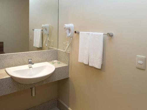 a bathroom with a sink and a mirror and towels at Days Inn by Wyndham Linhares in Linhares