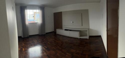 Habitación vacía con cocina y suelo de madera. en Apartamento no Centro en Siqueira Campos