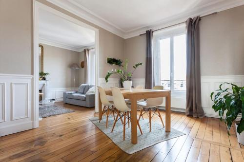 een woonkamer met een houten tafel en stoelen bij Appartement calme avec cachet (20 min de Paris) in Maisons-Laffitte