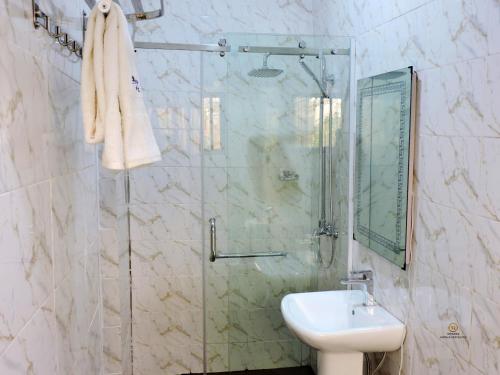 een badkamer met een wastafel en een glazen douche bij MOSANG HOTELS & SUITES in Aba