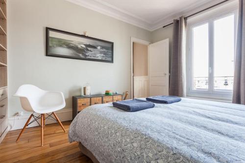 een slaapkamer met een bed met twee blauwe kussens erop bij Appartement calme avec cachet (20 min de Paris) in Maisons-Laffitte