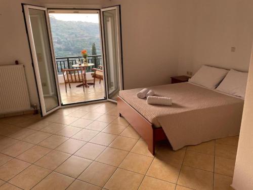 a bedroom with a bed and a balcony with a table at Loukas Apartments in Karavostamo