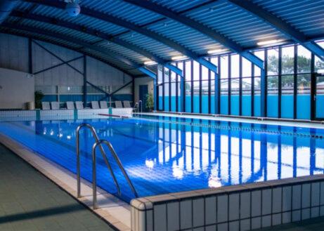 a large swimming pool with blue water in a building at Chalet ZonZeeSion T12 with Bikes! in Buren