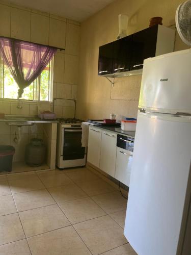 Il comprend une cuisine équipée d'appareils électroménagers blancs et d'un réfrigérateur blanc. dans l'établissement Pousada Recanto do Zeca casa 3, à Praia Grande