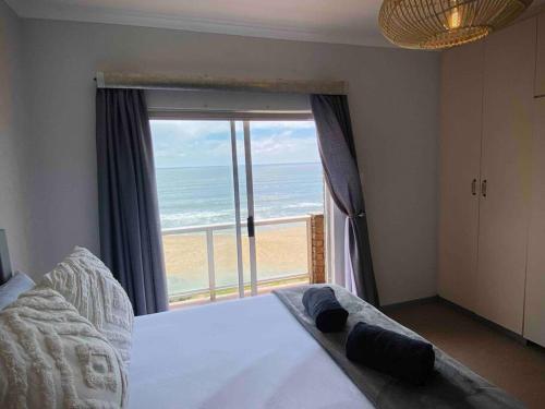 a bedroom with a bed with a view of the beach at Beachfront 3 bedroom house in Hentiesbaai