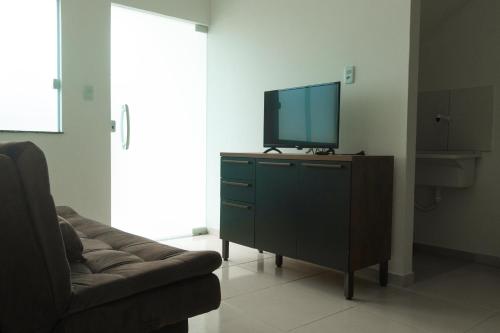 a living room with a tv on a dresser with a couch at Residencial Sales in Guaibim