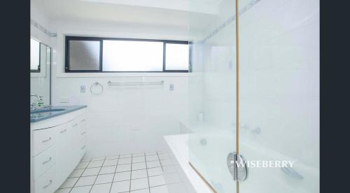 ein weißes Bad mit einer Dusche und einem Waschbecken in der Unterkunft Luxurious and spacious home in taree in Taree