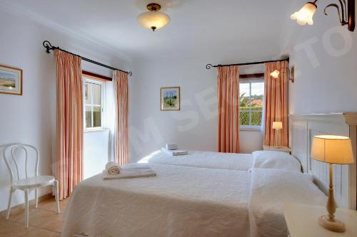 a white bedroom with two beds and a chair at Jardim Secreto in Luz