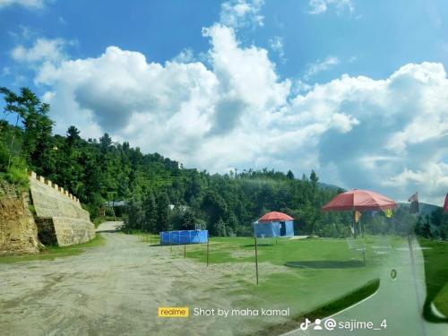 a golf course with two umbrellas in a field at Ihram Hotel And Guest House in Swat
