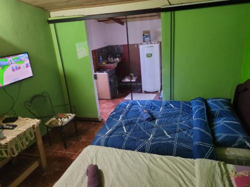 1 dormitorio con cama y pared verde en Apartamento Monoambiente a 15 min del Aeropuerto zona Shopping Mariano, en Colonia Mariano Roque Alonso