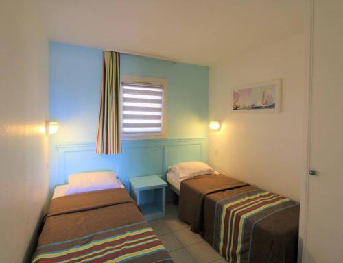 une petite chambre avec deux lits et une fenêtre dans l'établissement GASMIC - Appartement pour 4 personnes avec piscine et accès direct à la plage situé aux marines de Gassin, à Gassin