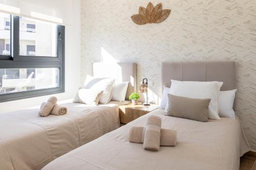 2 camas blancas en una habitación con ventana en VillaMartin Casa hermano, en Villamartin
