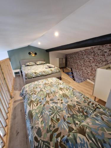 a bedroom with two beds and a brick wall at Chez Lilo in Fos-sur-Mer