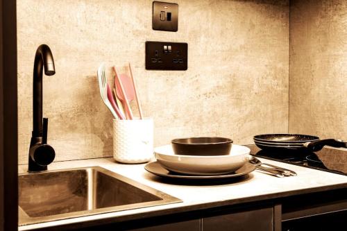 - une cuisine avec un évier, 2 casseroles et des ustensiles dans l'établissement Superior 1 Bed Studio 1D near Royal Infirmary & DMU, à Leicester