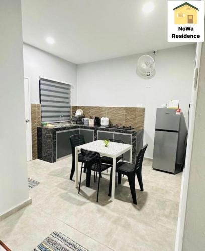 La cuisine est équipée d'une table, de chaises et d'un réfrigérateur. dans l'établissement NoWa Residence Rumah Kuning, à Mersing