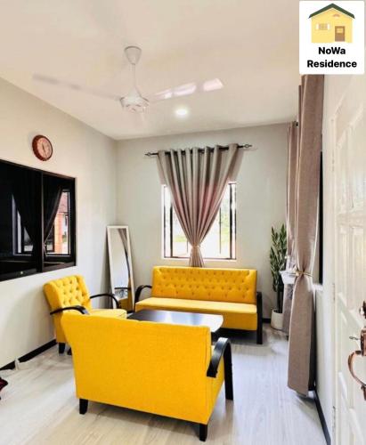 a living room with a yellow couch and a table at NoWa Residence Rumah Kuning in Mersing