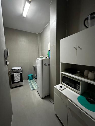 uma pequena cozinha com armários brancos e um frigorífico em 3 quartos Copacabana no Rio de Janeiro