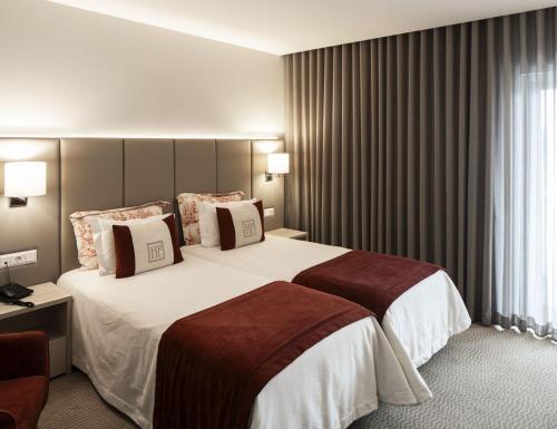 a hotel room with a large white bed with pillows at Hotel Fatima Center in Fátima