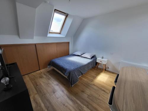 een kleine slaapkamer met een bed en een raam bij Châteaubourg : Studio avec cuisine et salle d'eau in Châteaubourg