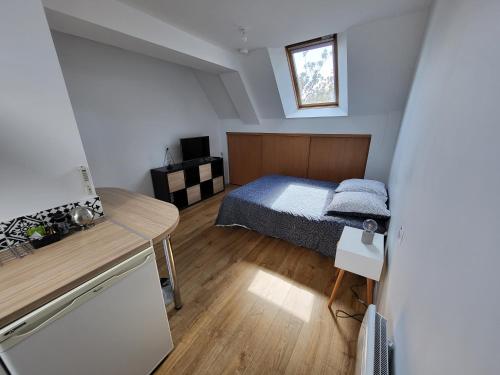 een kleine slaapkamer met een bed en een tafel bij Châteaubourg : Studio avec cuisine et salle d'eau in Châteaubourg