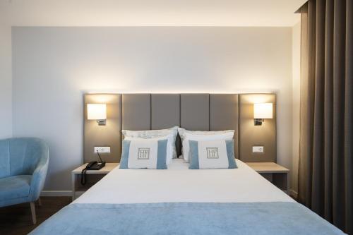 a bedroom with a large bed and a blue chair at Hotel Fatima in Fátima