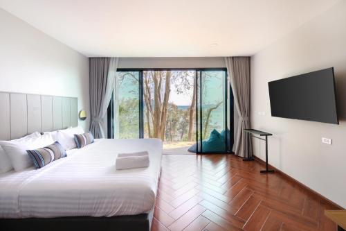 a bedroom with a large bed and a flat screen tv at Nature Vista Rawai in Nai Harn Beach