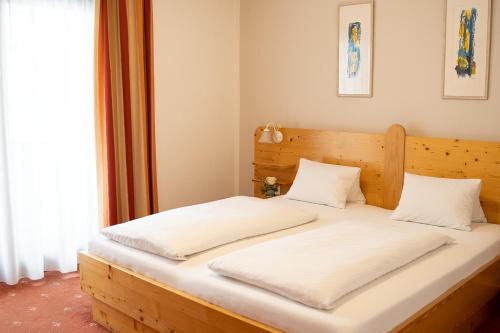 フェルトキルヘン・イン・ケルンテンにあるPension Fischingerのベッドルーム1室(白いシーツが備わる木製ベッド1台付)