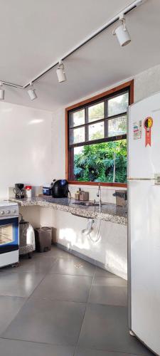 eine Küche mit einem Kühlschrank und einem Fenster in der Unterkunft Apartamento pé na areia com vista para o Mar de Itaipu in Niterói