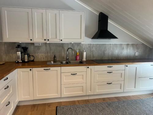 a kitchen with white cabinets and a sink at Mysig lägenhet på landet. in Ljung