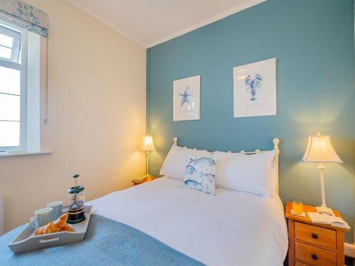 una camera con un letto bianco e una parete blu di The Lobster Pot a Trevor