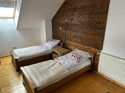 two twin beds in a room with wooden walls at Apartament D&D in Gorlice