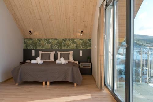 a bedroom with a bed and a large window at Wiktoria Residence Krynica-Zdrój in Krynica Zdrój