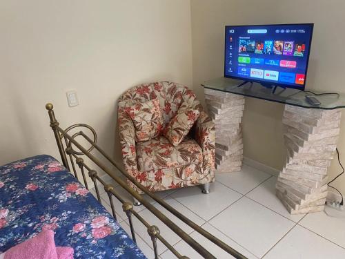 un salon avec une chaise et une télévision dans l'établissement Quarto Casal, Wi-Fi, Piscina, Praia, à Vila Velha