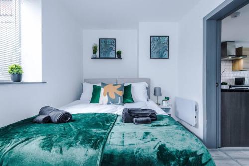 a bedroom with a large bed with a green blanket at Elegant & Comfortable 1-BR Flat by Amazing Spaces Relocations Ltd in Warrington