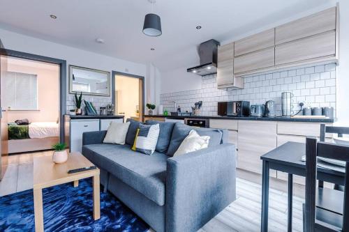 a living room with a blue couch and a kitchen at Elegant & Comfortable 1-BR Flat by Amazing Spaces Relocations Ltd in Warrington