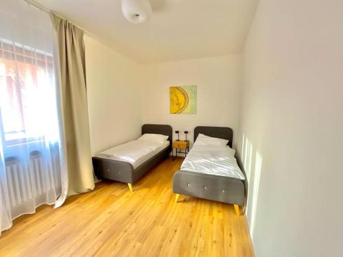 two beds in a room with wooden floors and a window at Apartmán č.5 v bankovním domě in Kutná Hora