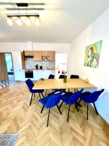 a dining room with a table and blue chairs at Apartmán č.5 v bankovním domě in Kutná Hora