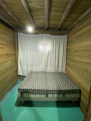 Ce lit se trouve dans une chambre en bois dotée d'une fenêtre. dans l'établissement Hostel formigueiro, à Imbituba