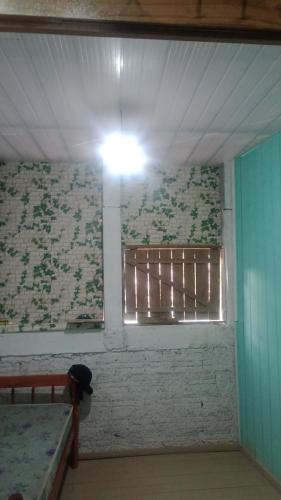 Cette chambre est dotée d'un mur avec une fenêtre et une lumière. dans l'établissement Hostel formigueiro, à Imbituba