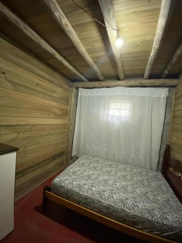Cama pequeña en habitación con pared de madera en Hostel formigueiro en Imbituba