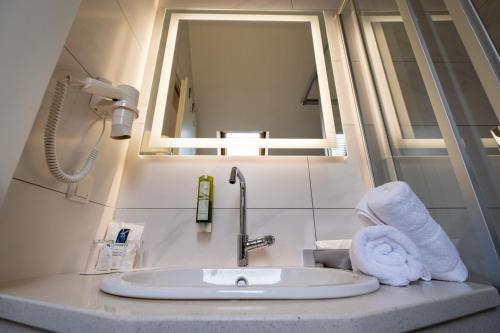 een wastafel met een spiegel en een handdoek bij Landhotel Rose am Plauer See garni in Plau am See