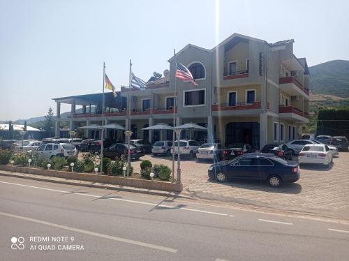 a large building with cars parked in a parking lot at Ble Alb in Udënisht
