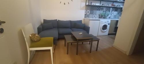 een kleine woonkamer met een blauwe bank en een tafel bij Lovely 1 bedroom apartment near Eye of Tirana in Tirana