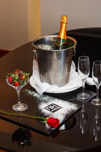a bottle of champagne in a bucket on a table with glasses at NH Collection Curitiba in Curitiba