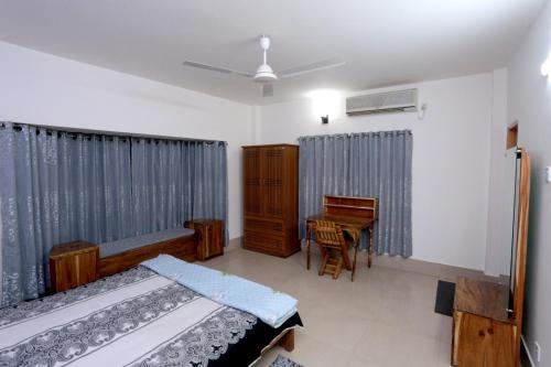 a bedroom with a bed and a desk and a table at Nirapod Holiday Homes in Sylhet