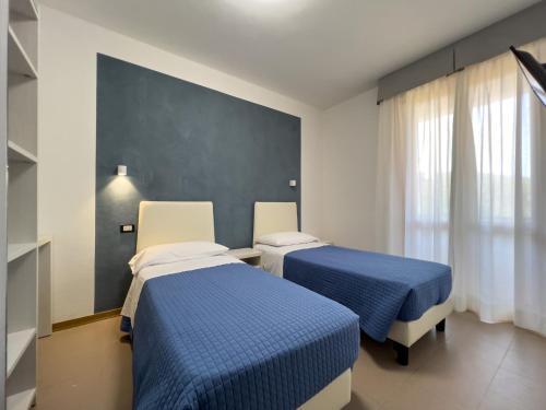 two beds in a hospital room with blue sheets at Hotel Brigantino in Procchio