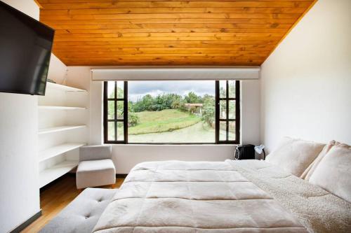 een slaapkamer met een groot bed en een groot raam bij Casa con huerto orgánico. in Subachoque
