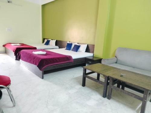 two beds in a room with a table and a couch at HOTEL OASIS PALACE in Dālkola